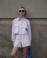 a lady wears a purple crop jacket with matching shorts